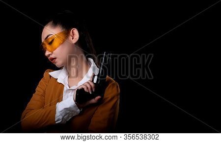 Portrait Beautiful Asea Woman Wearing A Yellow Suit One Hand Holding Pistol Gun At The Black Backgro