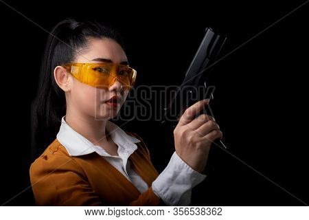 Portrait Beautiful Asea Woman Wearing A Yellow Suit One Hand Holding Pistol Gun At The Black Backgro