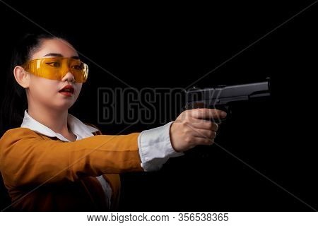 Portrait Beautiful Asea Woman Wearing A Yellow Suit One Hand Holding Pistol Gun At The Black Backgro