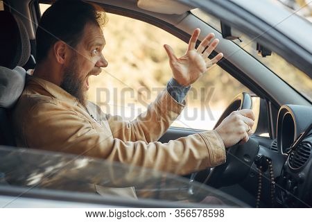 Crazy Angry Man Annoyed While Driving A Car. Mad Agrressive Driver Screaming Irritated With Traffic