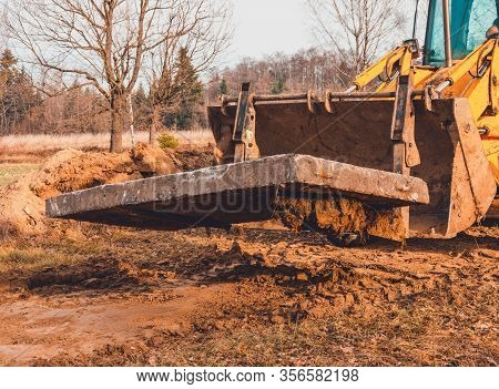 The Yellow Excavator Transports Concrete Slabs In The Countryside.