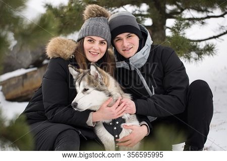Beautiful Family, A Man And A Girl In Winter Forest With Dog. Play With The Dog Siberian Husky.
