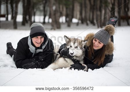 Beautiful Family, A Man And A Girl In Winter Forest With Dog. Play With The Dog Siberian Husky.