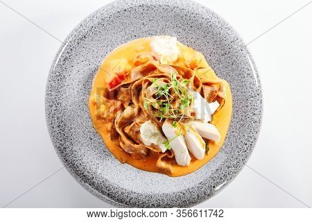 Spaghetti with baked tomato and chicken. Served traditional Italian cuisine. Borodinsky flour pasta with tomato sauce in plate. Italy culinary. Restaurant food portion, main course