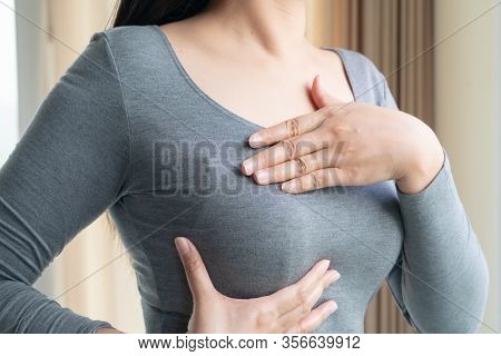 Woman Hand Checking Lumps On Her Breast For Signs Of Breast Cancer. Women Healthcare Concept.