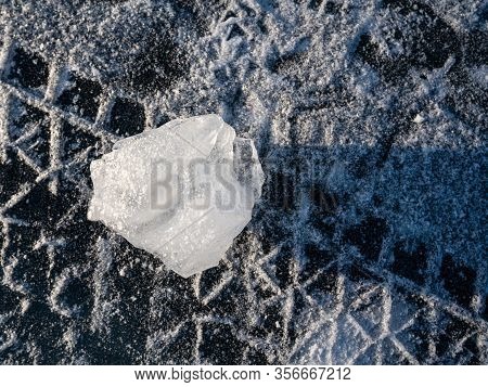 Closeup Unusual Shapes Ice Cube On The Frozen Lake Surface. Tire Tracks Run On Snow-covered Areas. L