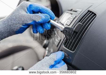 Man Hands Using Cleaning Brush And Removing Dust From Car Air Conditioning Vent Grille. Car Detailin