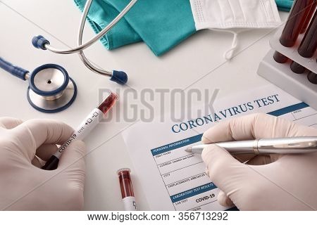 Doctor Filling Out Coronavirus Test Form On The Laboratory Bench With Blood Samples To Analyze. Top 
