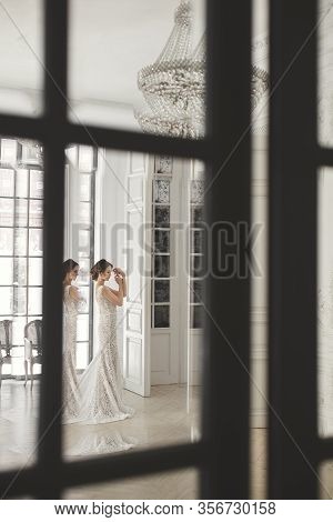 Beautiful Bride Posing In Wedding Dress In A White Photo Studio. Mirror. Sofa. Bouquet. The Door. Ch