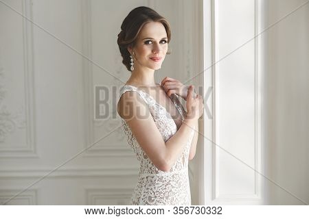 Beautiful Bride Posing In Wedding Dress In A White Photo Studio. Mirror. Sofa. Bouquet. The Door. Ch