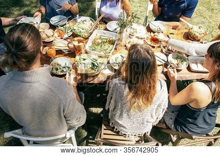Young Friends At Table Outdoor. High Angle View Of Male And Female Friends Gathering Around Table Wi