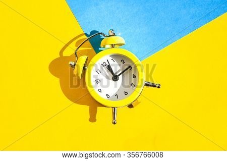 Yellow Vintage Alarm Clock On A Blue And Yellow Background With Selective Focus, Copy Space For Text