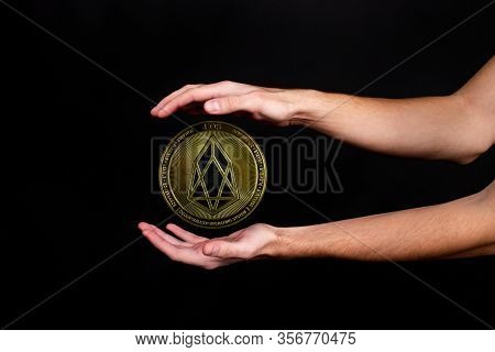 The Symbol Of The New Popular Cryptocurrency Eosio With The Image Of Hands On Dark Background