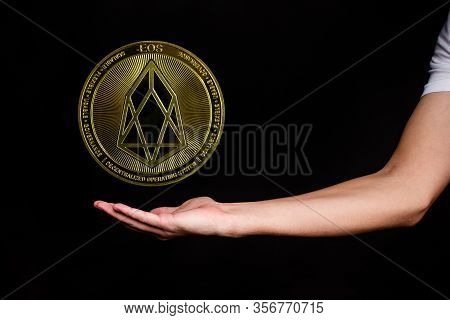 The Symbol Of The New Popular Cryptocurrency Eosio With The Image Of Hands On Dark Background