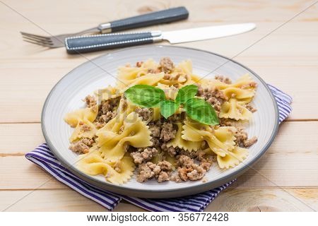 Ready-to-eat Pasta Navy With Minced Meat And Basil Leaves On A Plate And Cutlery On A Wooden Table. 
