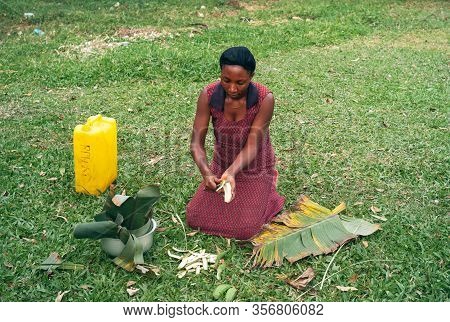 Kabale, Uganda - July 24 2011: Woman Kneeling And Preparing Cooking Banana. Black Local, Female Cook