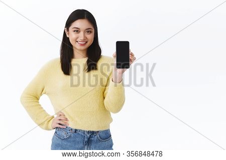 Kawaii Asian Girl With Short Dark Hair Holding Mobile Phone And Showing Smartphone Screen, Advertise