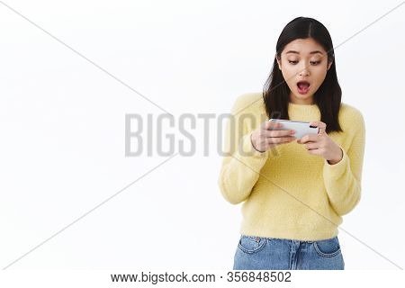 Tensed And Excited Asian Girl Trying Pass Difficult Level In Mobile Game, Turning Smartphone Sideway