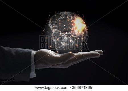 Businessman Holding World With Orange Flare On Black Background. Worldwide Business Globalisation.
