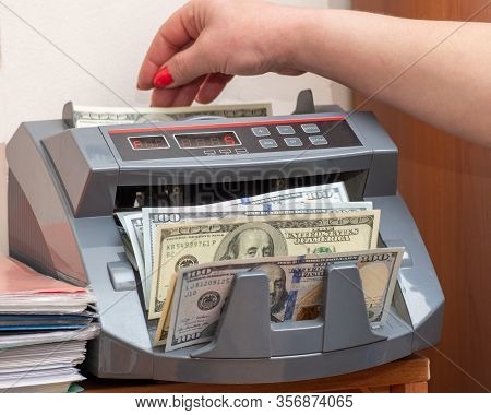 Woman Cashier Putting One Hundred Dollars American Banknotes Into Currency Counter At Checkout Count