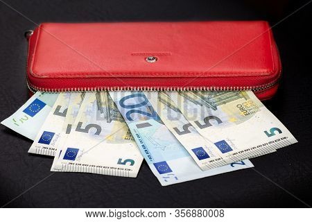 Close Up Of Bundles Of Euro Banknotes And Opening A Red Wallet On A Dark Background. Selective Focus