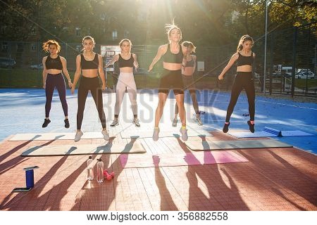 Front View Of Pretty Slender Muscular Girls In Sportswear Which Doing Special Jumping Exercises With