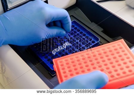 Loading A Dna Tube Into A Pcr (polymerase Chain Reaction) Thermocycler Machine In A Bioscience Labor