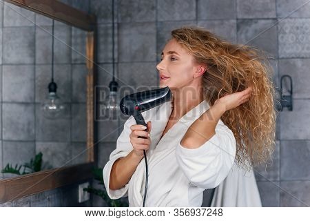Charming Smiling Lady With Light Curly Hair In White Dressing Gown Looking At Her Reflection In The 
