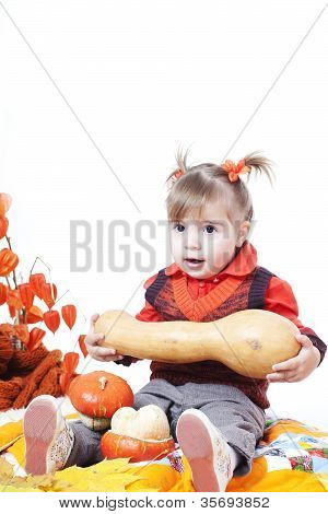 kleines Mädchen in eine orange Weste spielt mit großen Kürbisse