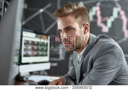 Close Up Portrait Of Successful Trader Looking Focused While Sitting In Front Of Monitors In The Off