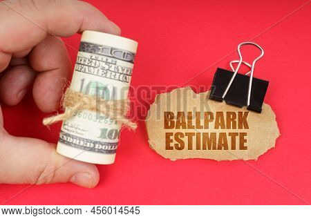 Business Concept. The Man Has Dollars In His Hands, On A Red Surface There Is A Cardboard Sign With 