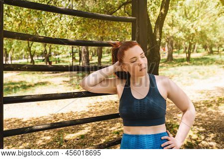 Young Woman Athlete, Resting After Training On An Outdoor Trellis. Athlete Practising Outdoor Sport.
