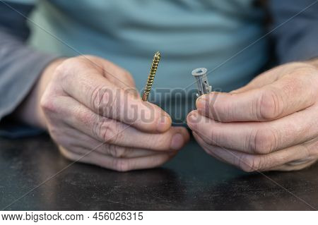 An Adult Male Is Holding An L-type Screw With A Dowel. A Screw With A Hook Is Used For Mounting On W