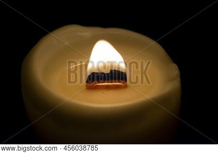 A Close-up Of A Burning Candle. The Candle Burns In A Dark Room. Black Background . Candle With Wood