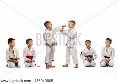 Little Beginner Karate Fighters In White Doboks And Colorful Belts Training Isolated On White Backgr