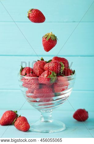 Strawberries Fall In Glass Cup On Blue Background. Vertical Photo. Top View