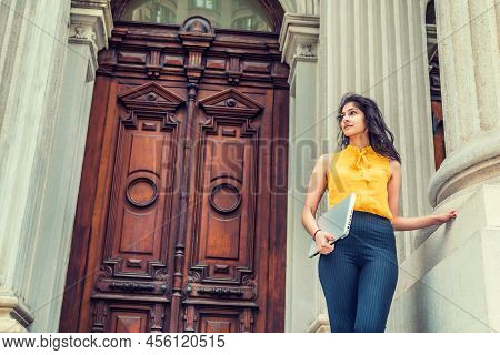 Modern East Indian American Business Woman. Wearing Sleeveless Orange Shirt, Arm Carrying Laptop Com