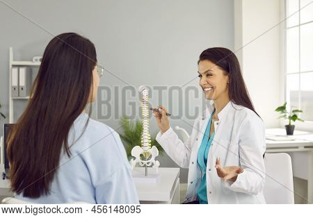 Friendly Female Physiotherapist In Hospital Office Advises Young Woman On Intervertebral Hernia.