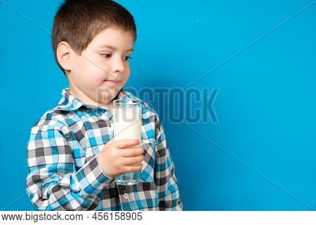 A 4-year-old Boy Holds A Glass Of Milk And Squirms Looking Into The Camera. Cows Milk Protein Allerg