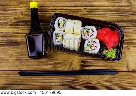 Uramaki Sushi Rolls With Surimi In Plastic Box On Wooden Table. Top View. Sushi For Take Away Or Del