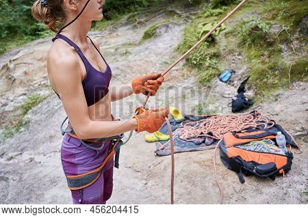 Close Up Of Young Female Climber Belaying Leader During Rock Climbing Outdoors, Using Rope, Grigri, 