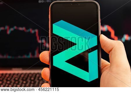 Zilliqa Zil Cryptocurrency Logo On The Screen Of Smartphone In Mans Hand With Downtrend On The Chart