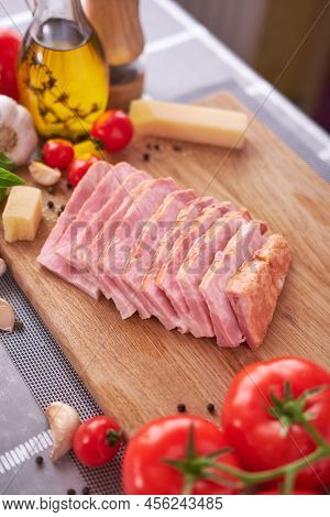 Sliced Pancetta Ham Bacon On Wooden Cutting Board At Domestic Kitchen