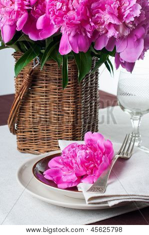 Configuração de tabela com peônias rosa, talheres Vintage e toalha de mesa marrom