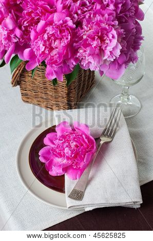 Configuração de tabela com peônias rosa, talheres Vintage e toalha de mesa marrom