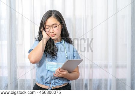 Concentrated Asian Glasses Woman Focus Looks At Her Tablet In Hand In Private Room In Work At Home P