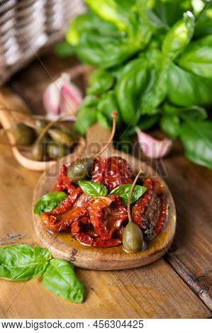 Dried Tomatoes In Olive Oil And Capers In Piala, Basil Next To The Product. Leaking Oil. Traditional