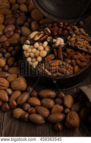 Mixed Nuts In A Tin And Burlap Sack Up Close On A Dark Wood Background