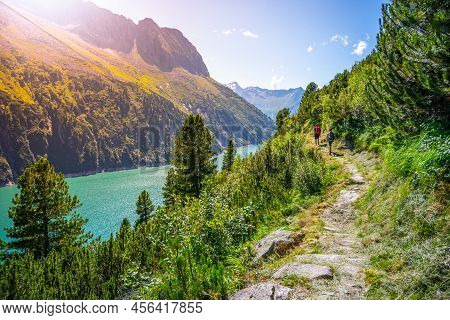 Alpine Track And Two Hikers At Vivid Blue Mountain Lake In Summer Alps. Speicher Zillergrundl Dam, Z