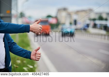 Close Up Of Two Mans Hands Hitchhiking By Roadside. Male Hands Showing Thumbs Up Gesture Outdoors On